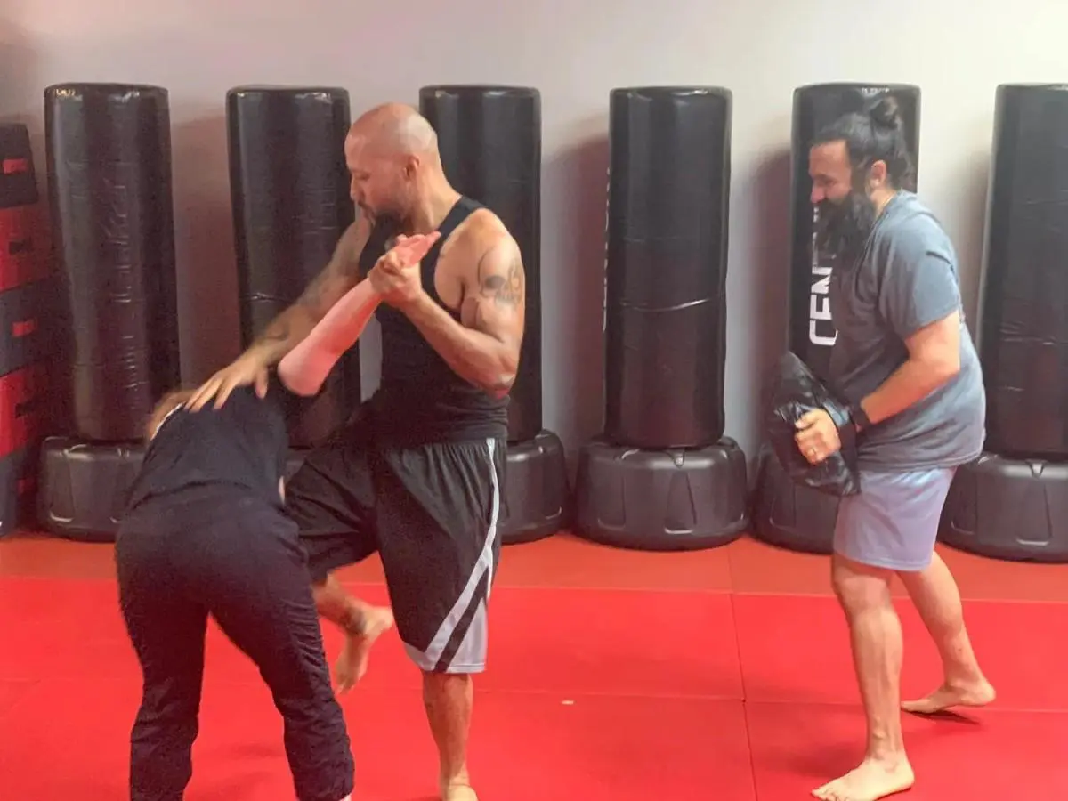 Martial arts instructor demonstrating a self-defense technique during class in a training gym.
