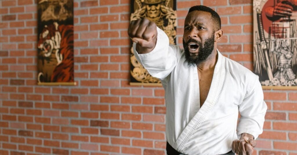 A powerful close-up of a bearded male martial artist in a white gi mid-punch with a focused expression, capturing the intensity of martial arts for beginners.